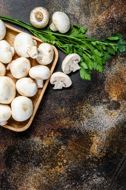 istock mushroom champignon in a bamboo bowl. Dark background. Top view.  Space for text 1251529658