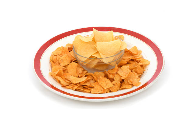 Bowl is full of tasty crispy potato chips isolated on white background. High resolution photo. Full depth of field.