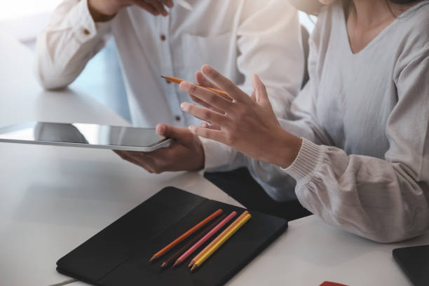 istock The female holding a colored pencil talking with the client to design or create using a freelance concept tablet to work. 1251532761