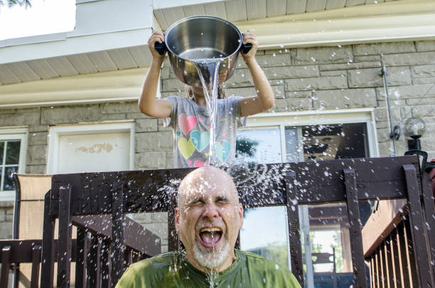 istock Girl dropping water on father's head 1251533791