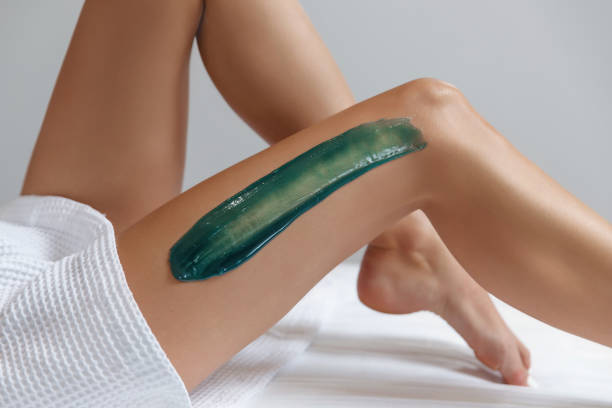 mujer joven depilando piernas con azúcar líquida en el centro de spa - leg waxing fotografías e imágenes de stock