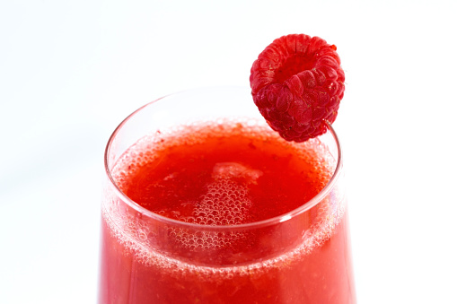Closeup of a raspberry juice in glass. Studio shot over white background.