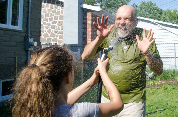 istock Girl wetting her dad with water hose 1251534552