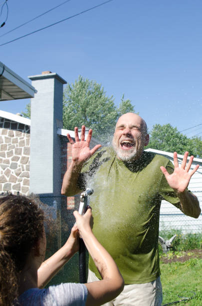 istock Girl wetting her dad with water hose 1251534656