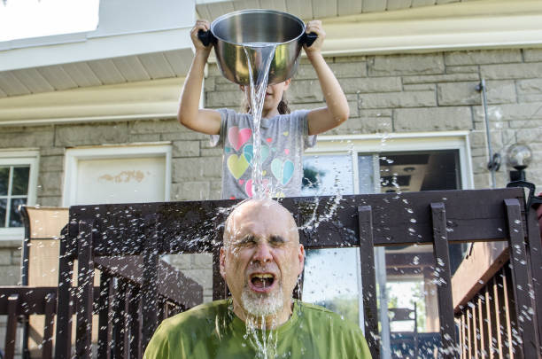 istock Girl dropping water on father's head 1251534674