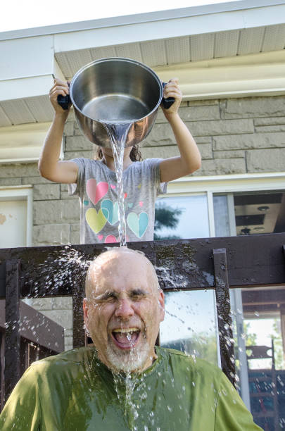 istock Girl dropping water on father's head 1251537494