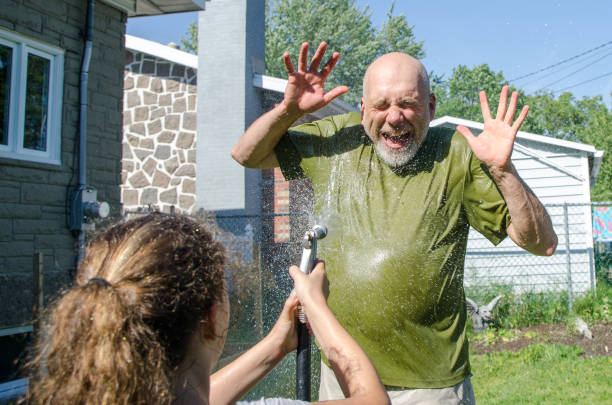 istock Girl wetting her dad with water hose 1251537906