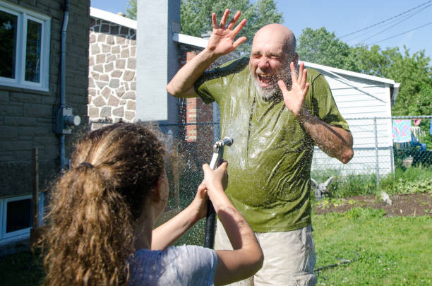 istock Girl wetting her dad with water hose 1251538202