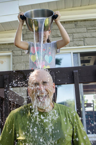 istock Girl dropping water on father's head 1251538281
