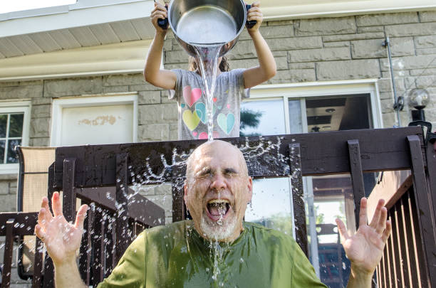 istock Girl dropping water on father's head 1251538360