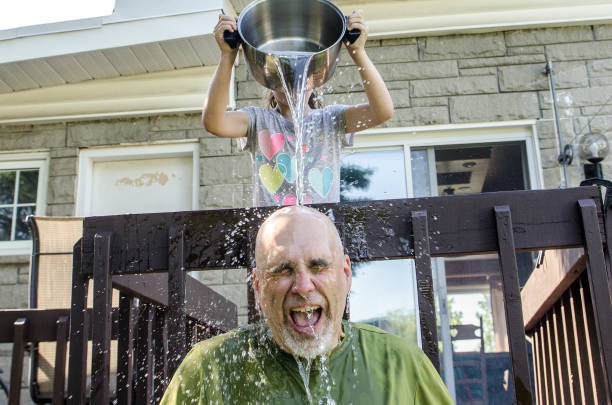 istock Girl dropping water on father's head 1251538383