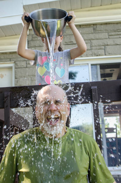 istock Girl dropping water on father's head 1251538412