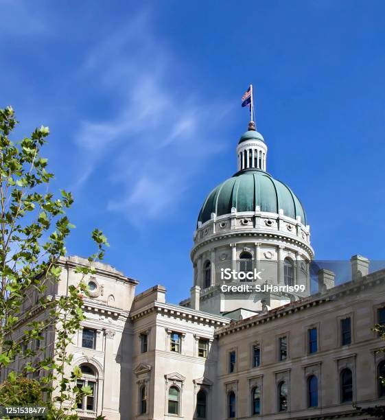 Downtown Indianapolis Indiana State Capital Building On A Blue Sunny Day With American Flag Flying Stock Photo - Download Image Now