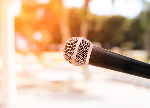 Microphone on abstract blurred of speech in seminar room or speaking conference hall light, sunset background