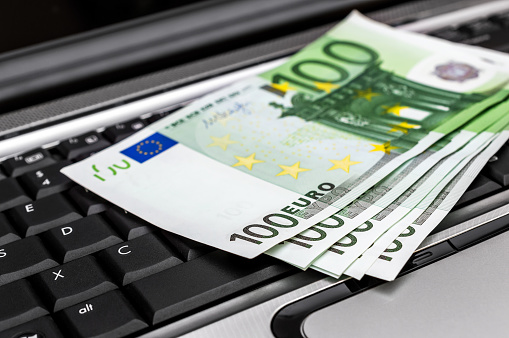 Euro bills on laptop keyboard.