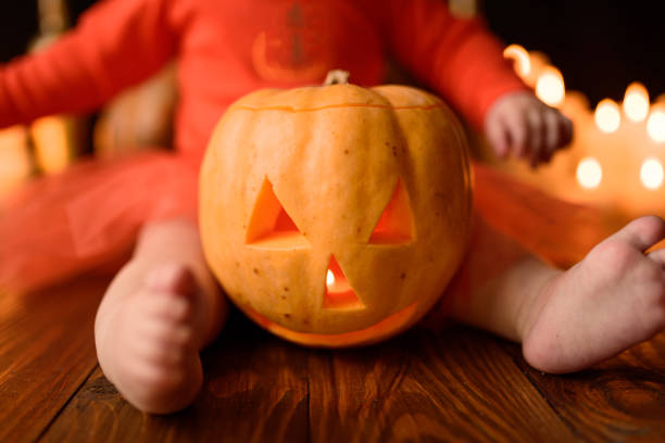 Pumpkin Jack close-up, near the legs of a little girl. stock photo