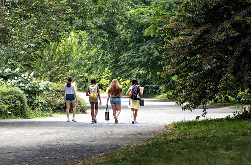 New York, NY, USA - June 22, 2020: Four teenaged friends walk happily together on the bridle path encircling the Jacqueline Kennedy Onassis Reservoir in Manhattan's Central Park. This day, June 22, is the first day of NYC's 