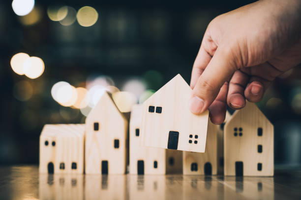 Hand choosing mini wood house model from model and row of coin money on wood table, selective focus, Planning to buy property. Choose what's the best. A symbol for construction ,ecology, loan concepts eligiendo a mano mini modelo de casa de madera de modelo y fila de dinero de la moneda en la mesa de madera, enfoque selectivo, planificación para comprar la propiedad. elige qué es lo mejor. un símbolo para la construcción, la ecología, los conceptos