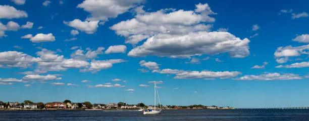 A sailboat in the Great South Bay with very blue sky and thick puffy white clouds above.
