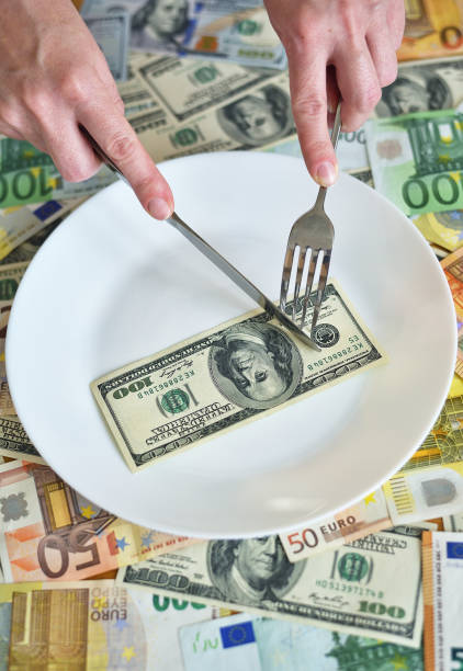 istock Dollar bills lie on a plate. Hand with a fork reaches for dollars 1251548569