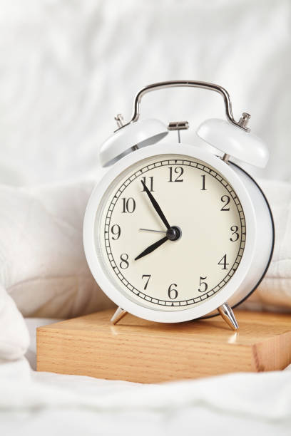 istock Alarm clock on the white bed. Close up. 1251549173
