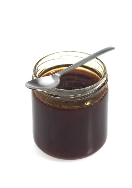 istock Pot of Molasses with Spoon against White Background 1251549269