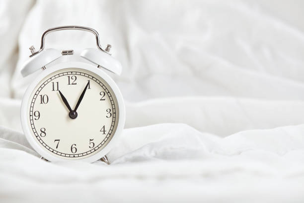 istock Alarm clock on the white bed. Close up. 1251550116