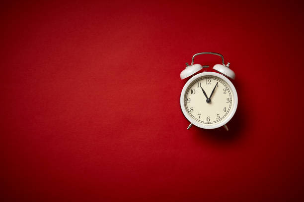 istock White alarm clock on red background. Close up. Top view. 1251550450