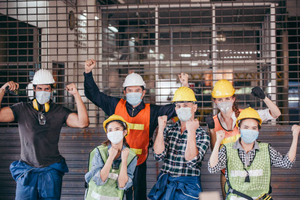 Happy group of engineer industrial worker wearing protective face mask celebrating after factory open. success business teamwork corporate industry people. lockdown ending. new normal working concept