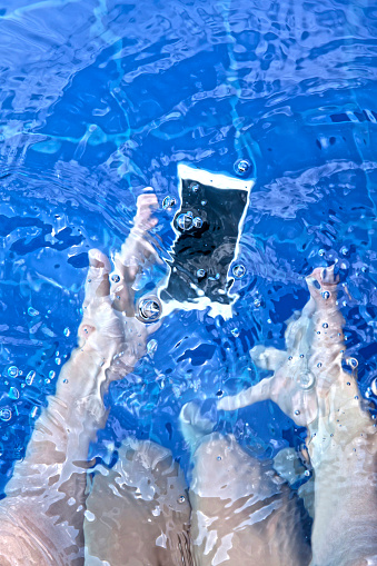 Unrecognizable woman panicking as she dropped her smartphone in swimming pool - Lifestyles
