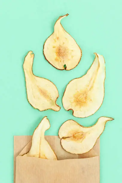 Photo of Dry slice fruits pear. Tasty dehydrated fruit chips for plant-based diet. Trendy food for vegetarian. Bright colors flat lay with copy space.