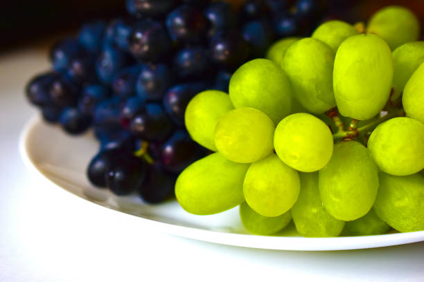 istock Black and green delicious grapes on a white plate close up 1251551839