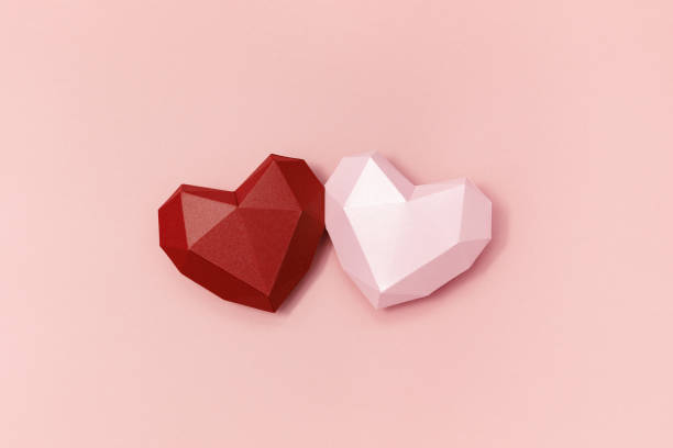 istock Red and pink polygonal paper hearts together on crem colored surface. Holiday background with copy space for Valentines Day. Love concept. Minimal style. 1251551849