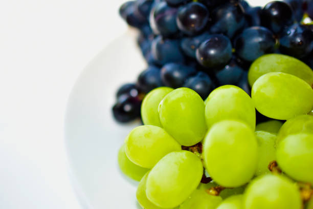 istock Black and green delicious grapes on a white plate close up 1251553580