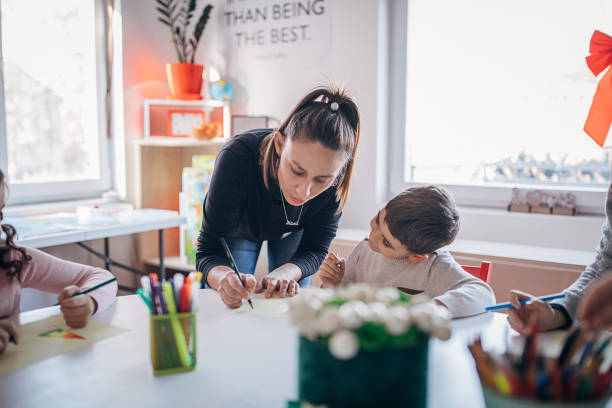 istock Female teacher with kids drawing on class in private school 1251554876