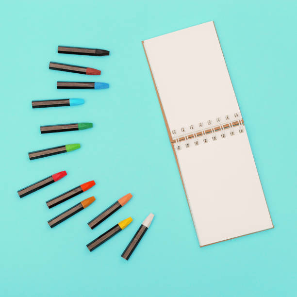 istock Top view of colored pastel crayons and open notebook on spring for drawing. Set of multicolored chalks for creativity. Work space for drawing. 1251554916