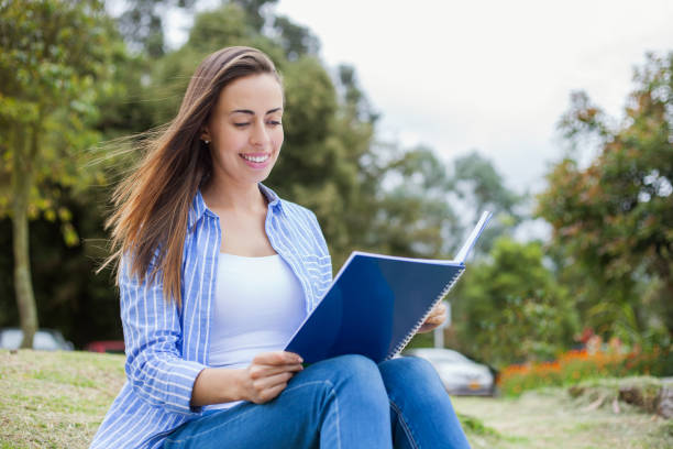 istock Beautiful young woman at a public park studying with her notebook 1251555536