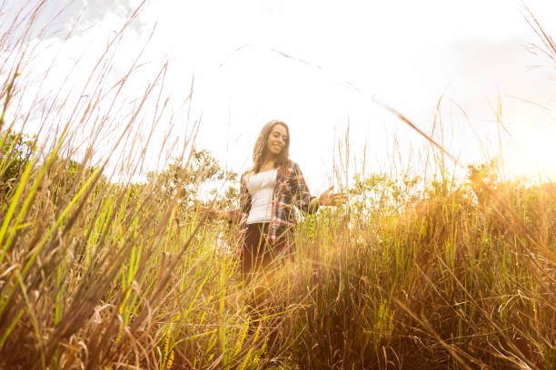 Beautiful woman walking through a field looking happy on a sunny day