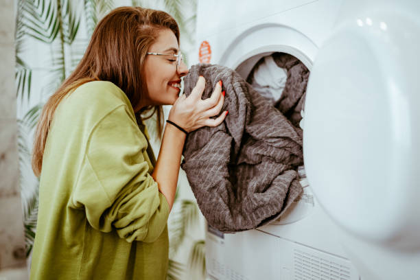 genç kadın evde çamaşırlarını yıkadı - washing machine stok fotoğraflar ve resimler