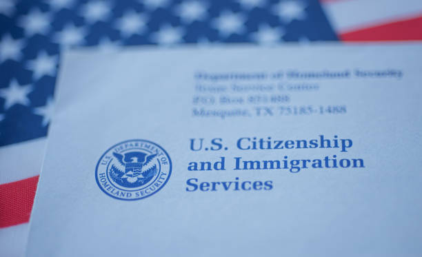 lettre de toucher à la main (enveloppe) de l’uscis sur le drapeau de fond des usa. - citizens photos et images de collection