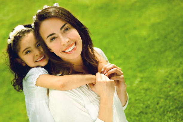 istock Loving daughter hugging mom from behind both smiling at camera 1251561380