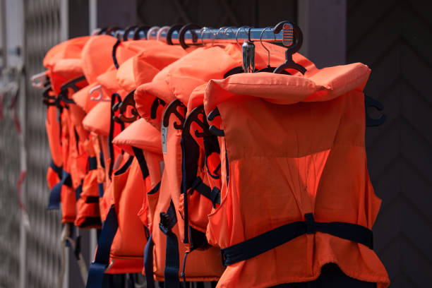 Close up of a large number of bright orange life vests hanging neatly in two rows on hooks given a nice aesthetic look