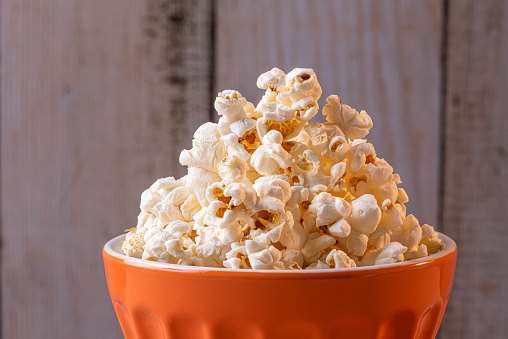 Popcorn in a bowl. Wood background
