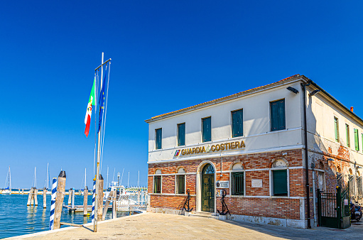 Chioggia, Italy, September 16, 2019: Italian coast guard building Capitaneria di Porto Guardia Costiera Comando COMPAMARE near embankment of lagoon, Veneto Region