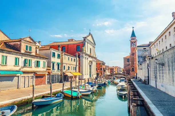 Photo of Chioggia cityscape with narrow water canal Vena with moored multicolored boats