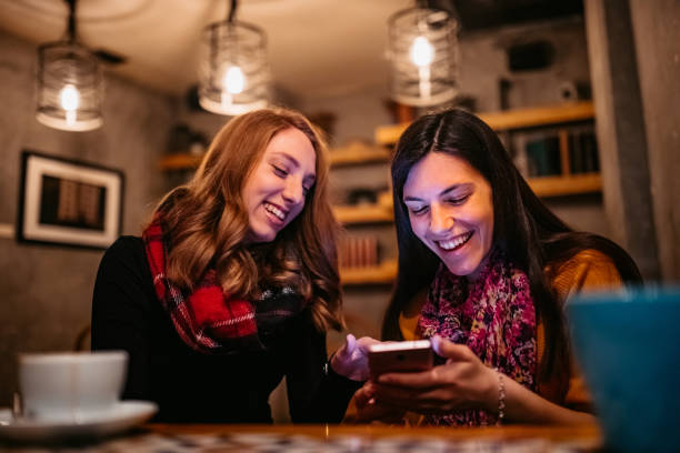 istock Two female friends using phone on coffee break 1251565514