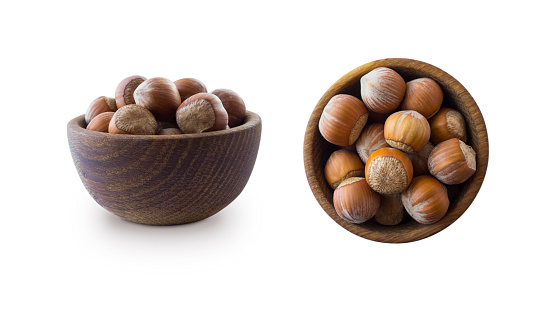Studio shot of hazelnuts on white background. Heap of hazelnut in nutshell isolated on white. Nuts in a bowl with copy space for text. Hazelnut close-up. hazelnut