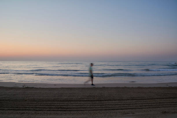 człowiek chodzenie na plaży o wschodzie słońca - sunrise beach couple hiking zdjęcia i obrazy z banku zdjęć