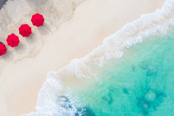 Beach umbrellas and blue ocean. Beach scene from above Beach scene - turquoise transparent ocean and red beach umbrellas on white sand beach. Bali beach aerial view. beach umbrella stock pictures, royalty-free photos & images