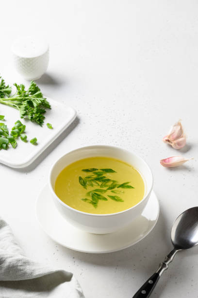 istock Chicken broth with greens in white bowl over white table. Copy space. 1251572979